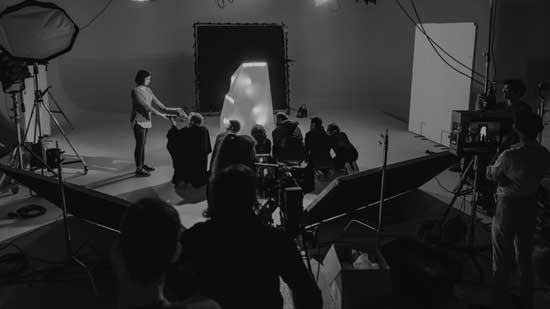 Soundstage shot with actors and crew gathered round filming a crucial scene